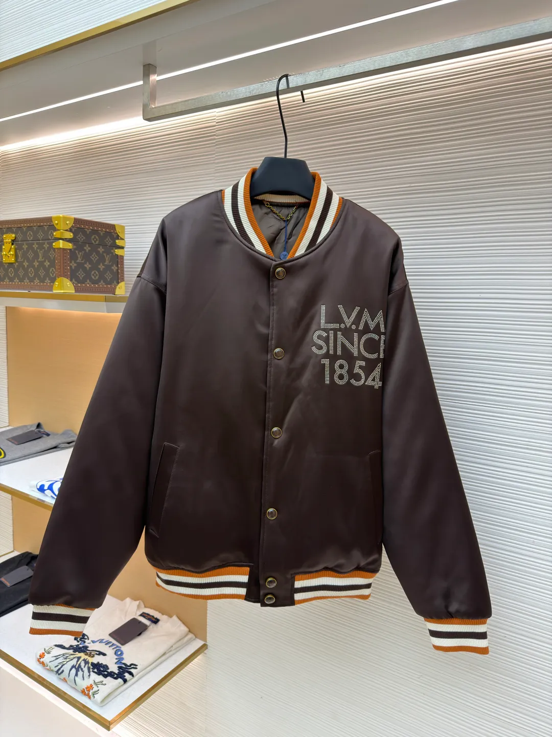 LOUIS VUITTON decorative flight jacket ●Original version: 30,000 purchased and developed ●Item number: 1682285-B90 ●Fabric: cotton fabric ●Technology: patch production ●Color: brown ●Version: fitted version ●Weight: about 1085 grams ●Size: 46-48-50-52 ●Description: The main body of this Louis Vuitton satin baseball jacket is made of high-density matte satin fabric, which has been treated with anti-wrinkle shaping technology. The fabric has a strong drape and is not easy to wrinkle. The dark brown background color is prepared by precision dyeing and finishing technology, giving it a rich color and high-end texture. The "L.V.M SINCE 1854" logo on the left chest is made with hot-drilling technology. High-quality rhinestones are used for precise hot-pasting in different areas. The diamond surface is shiny and strong and will not fall off easily. The ribbed splicing of the collar, cuffs and hem is a three-color contrasting design. It is woven with high-elastic knitted yarn, which will not easily loosen and deform after long-term wear. The placket is equipped with custom-made metal snaps. The hardware is thick and anti-oxidation. The overall style is loose and off-shoulder. The splicing is covered with blind stitching technology, and the wiring is smooth and traceless. Every craft detail follows the brand's luxury product production standards, taking into account both design and wearing comfort. The overall wiring is straight and delicate, the fabric is comfortable and soft, and the color is consistent without color difference. It can be matched with the same style to create a fashionable look and control various occasions. Customized accessories, complete with three standards, same style for men and women!